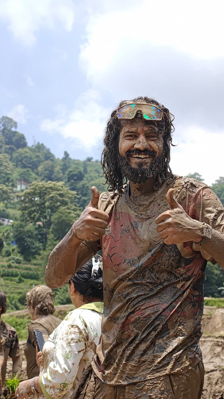 Anurag covered head to toe in mud, grinning, both thumbs up