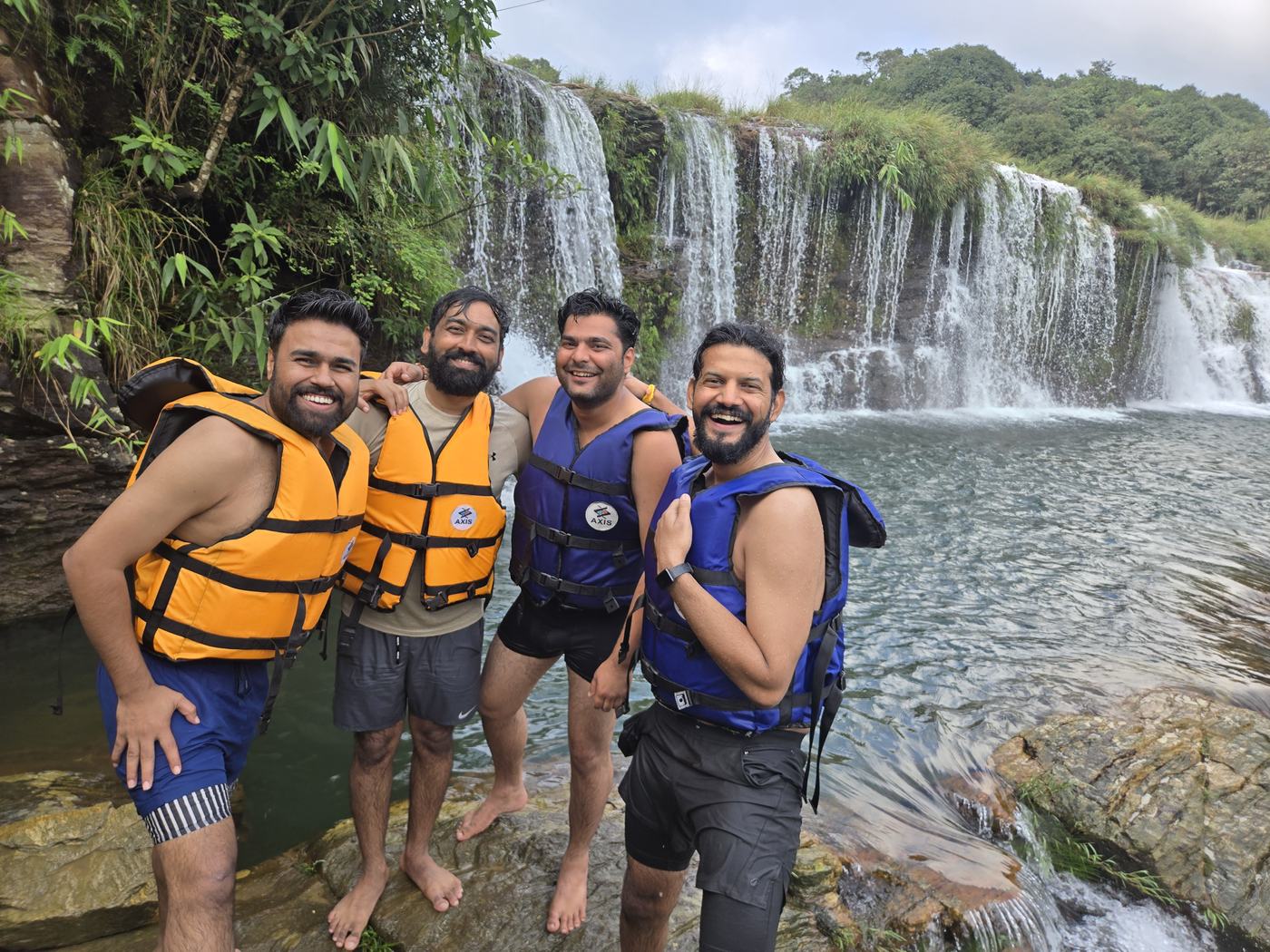 A group in life jackets standing in front of a waterfall
